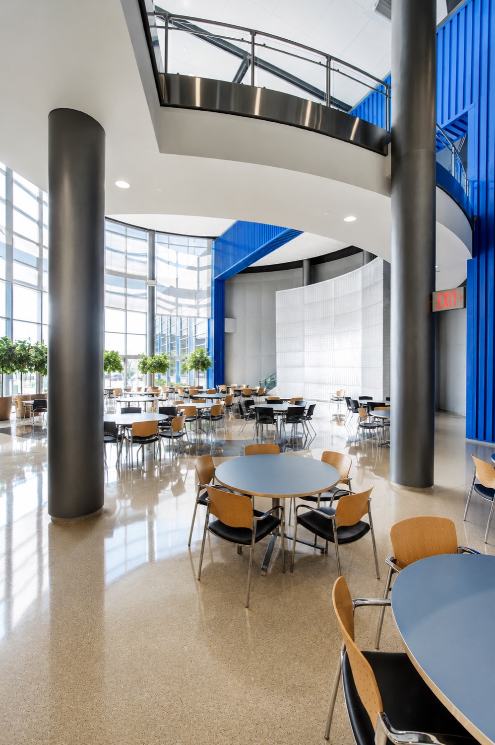 The Center's light-filled atrium with café seating beneath sculptural columns and a sweeping blue staircase